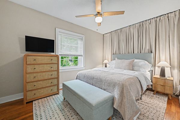 Bedroom in Apartment 3S with queen bed, rattan dresser, and TV